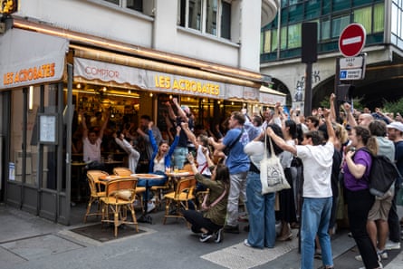Supporters and passers-by react as they watch the judo mixed team final between Japan and France at the terrasse of a bar in Paris.