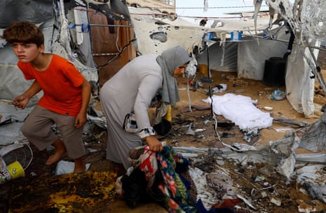 Palestinian people inspect the damage seen in the aftermath of an overnight Israeli airstrike on a tent in Gaza City.