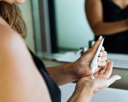 A woman applies cosmetics in the bathroom near the mirror