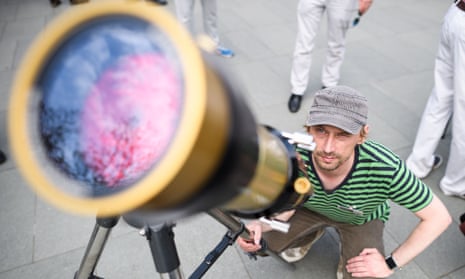 Mark Duwe looks through a telescope at Mercury moving in front of the sun