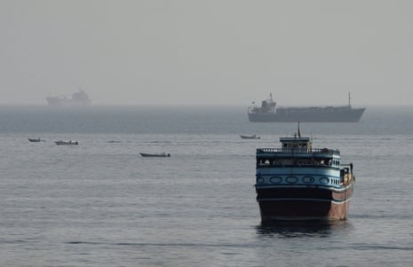 Ships and boats on water, with a large blue fishing vessel in the foreground