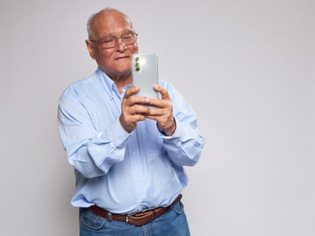 Elderly man looking at a phone held in front of him in both hands