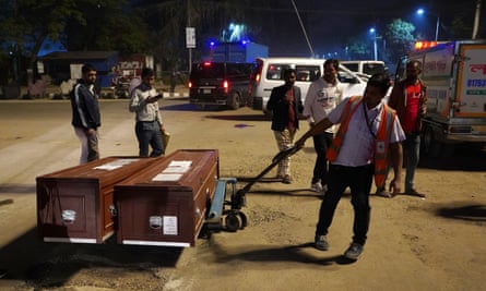 An airport worker pulling a trolley with two coffins