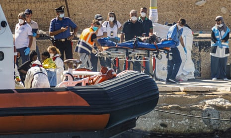 Survivors are helped from a rescue vessel on the Sicilian island of Lampedusa, Italy, on 21 October.