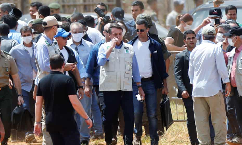President Jair Bolsonaro dispenses with a mask and touches his face as he visits a temporary field hospital, amid the coronavirus outbreak, in Aguas Lindas, state of Goias,Brazil, at the weekend,