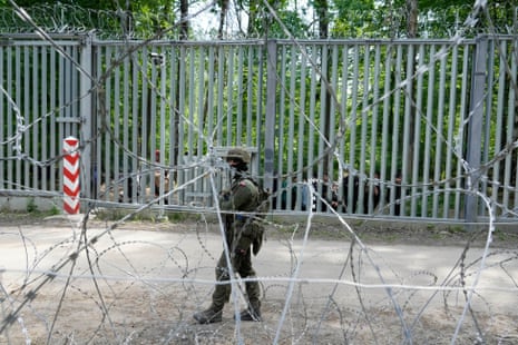A Polish soldier patrols the metal barrier border with Belarus, in Bialowieża Forest.