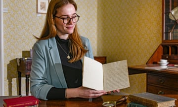 Museum officer Rebecca Wood holding open the manuscript by Frank Austen, with handwritten pages of text visible within