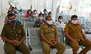 Sri Lankan public health officials and medical workers wearing facemasks wait for their turn to cast postal ballots for the parliamentary elections.