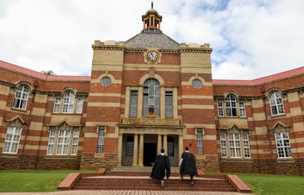 Two pupils walk up steps towards the front entrance of the school
