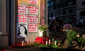 A demonstrator adds flora to a memorial for George Floyd and Breonna Taylor in Oakland.