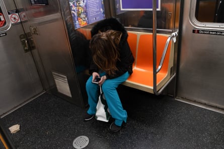 A medical worker uses her mobile phone while riding on the NYC subway during the coronavirus crisis.