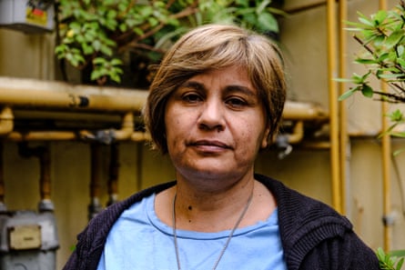 A serious-looking middle-aged Latina woman poses