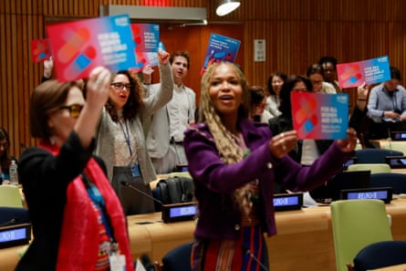People stand holding leaflets that say ‘For all women and girls: rights, equality empowerment’.