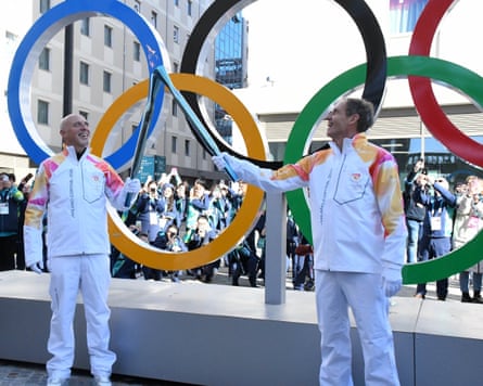 Ippolito Sanfratello and Hugo Herrnhof hold flaming torches in the Olympic village
