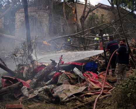 Firefighters at the scene in Kfar Roummane, southern Lebanon, after an Israeli strike on Monday