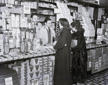 Two women talk to pharmacists behind the counter of a drugstore