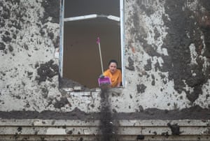A woman throws debris out of a window of a hospital damaged by a Russian missile strike in Kharkiv, Ukraine.