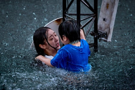A woman and young boy in flood water hanging on to a metal tower.