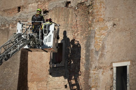 Firefighters on a crane work on the Torre dei Conti
