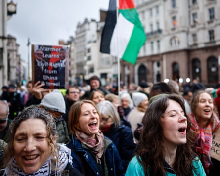 People chanting as one person holds a Palestinian flag