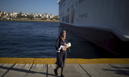 A migrant woman holds a child after arriving at the port of Piraeus near Athens.