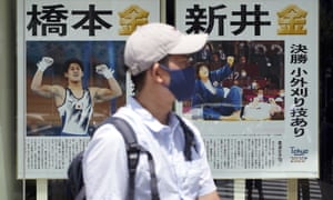 A man wearing a protective mask to help curb the spread of the coronavirus walks past extra papers reporting on Japanese gold medalists at the 2020 Summer Olympics, Thursday, 29 July 2021, in Tokyo, Japan.