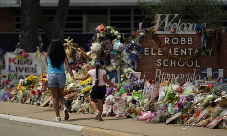 Visitors walk past a makeshift memorial honoring those recently killed at Robb Elementary School, Tuesday, July 12, 2022, in Uvalde, Texas. A Texas lawmaker says surveillance video from the school hallway where police waited as a gunman opened fire in a fourth-grade classroom will be shown this weekend to residents of Uvalde. (AP Photo/Eric Gay)