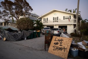 A sign reads 'loot and I shoot' outside a storm-damaged home in the wake of Hurricane Ian in Naples