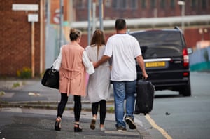 A family hold each other tightly as they walk away at first light from the Manchester Arena and Victoria railway station