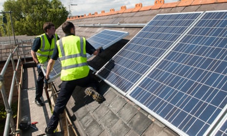 Workers install photovoltaic solar panels on the slate roof of a Victorian house in London