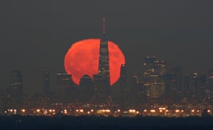 A hunter’s moon rises behind lower Manhattan and the One World Trade Center in New York City on Halloween