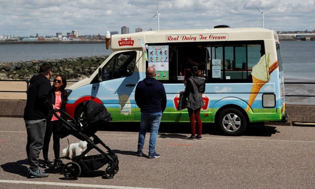 People queue to buy ice cream from an ice cream van in Liverpool.