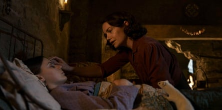 A woman comforts a girl sleeping in bed