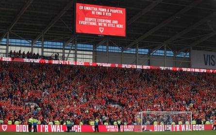 The big screen gives a translation of the words to the song Yma o Hyd as the Red Wall of Wales fans sing together after the win over Ukraine.