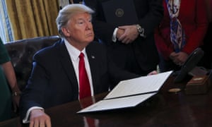 President Trump signing an executive order in the White House Oval Office.