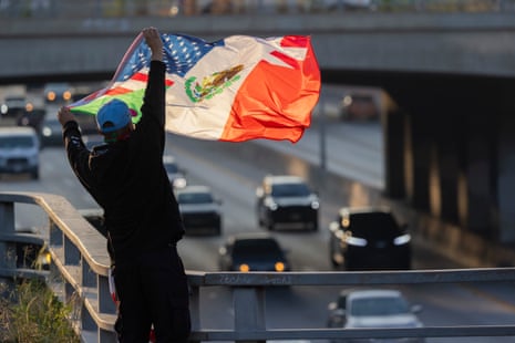 A man waves a half-Mexican and half-American flag over the 101 Freeway as protests continue in Los Angeles following three days of clashes with police after a series of immigration raids on June 09, 2025 in Los Angeles, California.