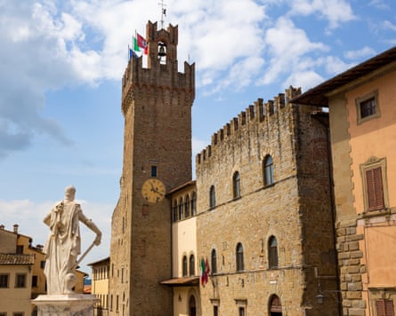 Medieval buildings and a tower in a square with a statue
