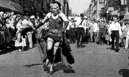 A man in drag heads a carnival procession down Old Compton Street during the Soho Fair in 1965