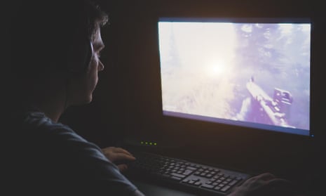 Man in headphones playing computer shooter game at night