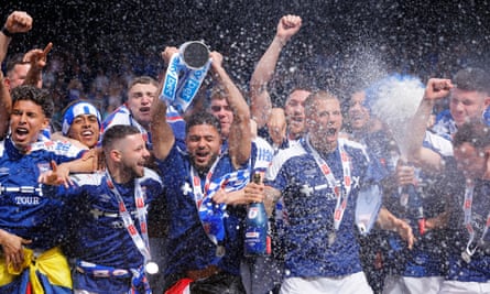 Ipswich Town captain Sam Morsy lifts the trophy as his teammates celebrate their team’s promotion to the Premier League.