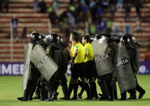 Police officers with riot shields protect referees after a football match in Bolivia