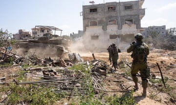 Israeli soldiers approach a ruined apartment building