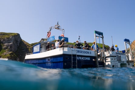 Two boats on the sea, with passengers and crew visible, at Lundy, Devon – the Obsession II and the Barbara B. The camera is shooting upwards from water level.