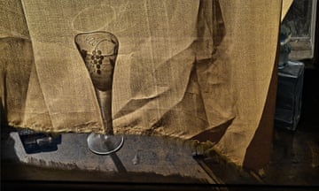The bottom of a wine glass and its silhouette behind a piece of material.