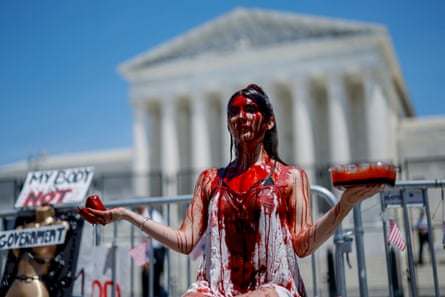 Un demonstrant pentru drepturile la avort este acoperit cu sange fals in timpul unui miting in fata Curtii Supreme, in iulie 2022.