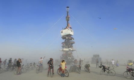 people around a sculpture, surrounded by dust