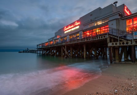 A view from the shoreline of Sandown pier lit up at dusk