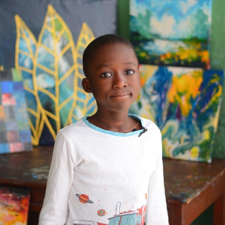 Fiyinfoluwa Adenij standing in front of some of his artwork. 