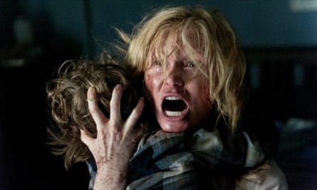 Woman screaming and holding a child with his back to the camera