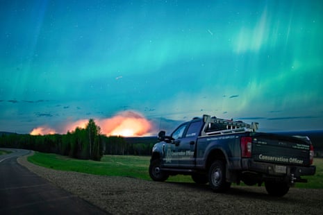 a wildfire burns beneath the aurora borealis